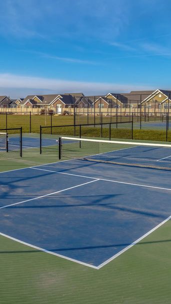 Wyczyść pionowe korty tenisowe na szerokim bujnym trawniku pod żywe błękitne niebo z chmur - Zdjęcie, obraz