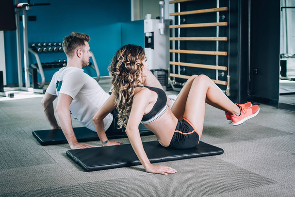 Mulher fitness atraente com treinador fazendo exercício duro no ginásio
 - Foto, Imagem