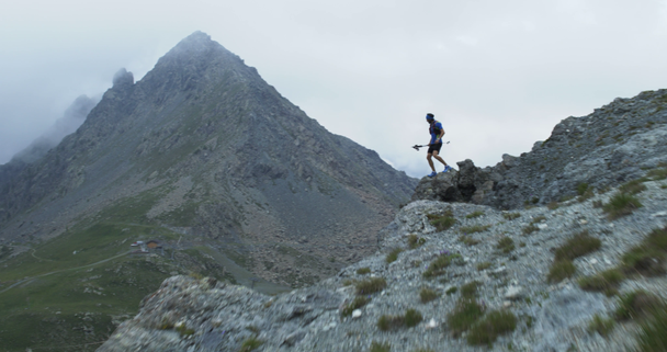 崖の端に達する男トレイルランナーは、岩の登りで山頂のピークトレーニングに走ります。曇りと霧の悪天候で屋外野生の緑の自然。活動、スポーツ、努力、挑戦、意志の概念 - 映像、動画