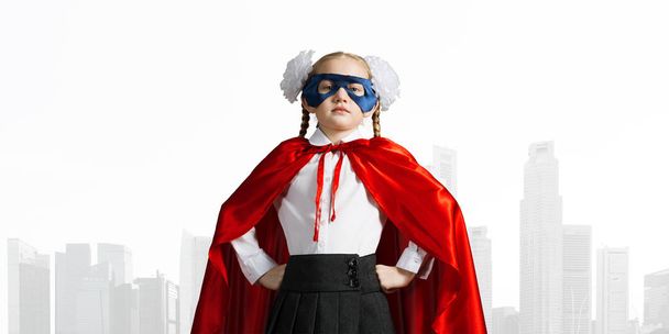Маленька впевнена дитина в масці і мисі грає крутого супергероя
 - Фото, зображення