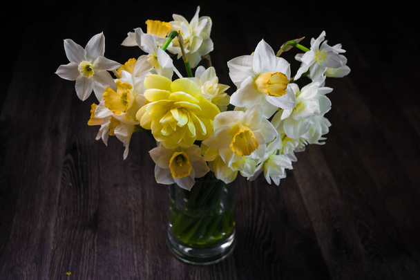 A bouquet of flowers on a dark wooden background. White narcissus in a vase. Place for your text. Top view. - Foto, Imagem