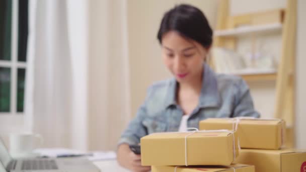 Умный азиатский молодой предприниматель бизнес-женщина владелец МСП онлайн проверки продукта на складе и сохранить на ноутбук, работающий на дому. Владелец малого бизнеса в концепции домашнего офиса
. - Кадры, видео