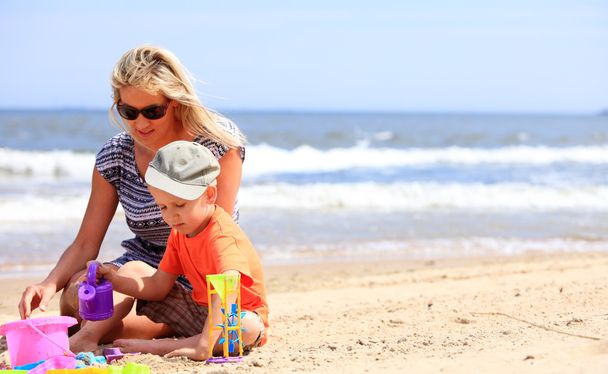 Anya játszik játékok a strandon és fia - Fotó, kép