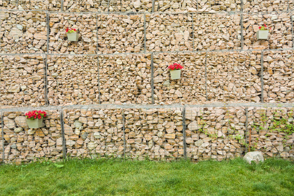 Valla de Gabion pared de malla de acero con piedras decoradas flores
. - Foto, Imagen