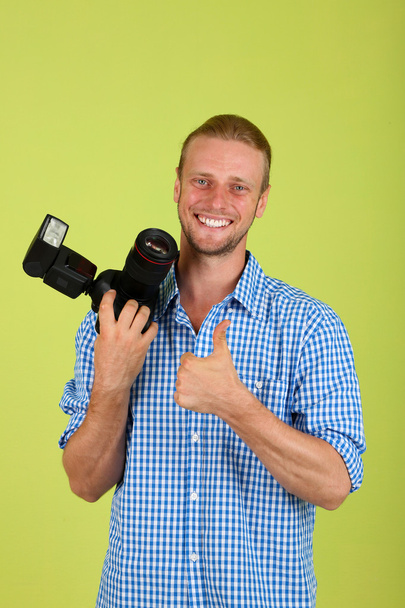 Handsome photographer with camera,on green background - 写真・画像