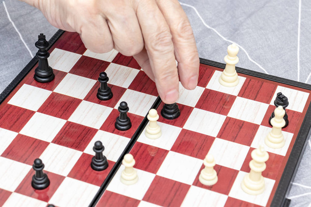 Hand of an elderly senior woman playing chess close up, entertainment and intellectual activity for retired people concept - Foto, imagen
