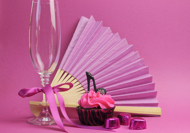 cupcake de fête rose avec chaussure à talons hauts stilleto noir avec verre de champagne, ventilateur et chocolats
 - Photo, image