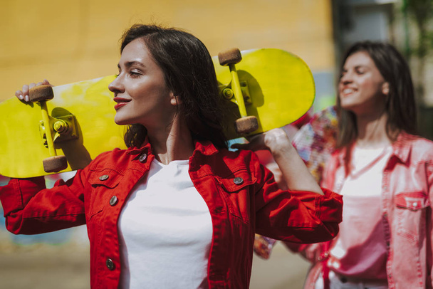 Pretty smiling hipster girl with yellow skateboard - Valokuva, kuva