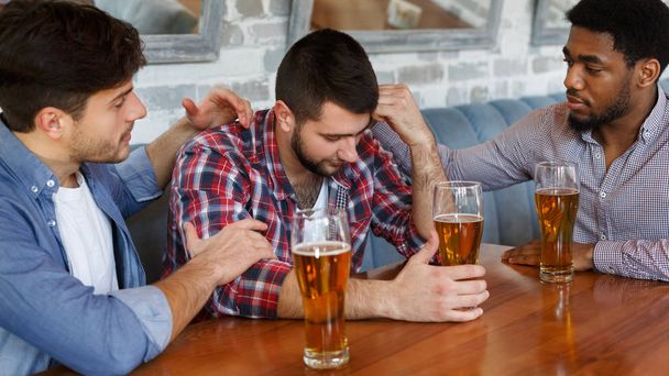 Παρηγορώντας τον θλιμμένο φίλο. Άντρες που πίνουν μπύρα και μιλούν - Φωτογραφία, εικόνα