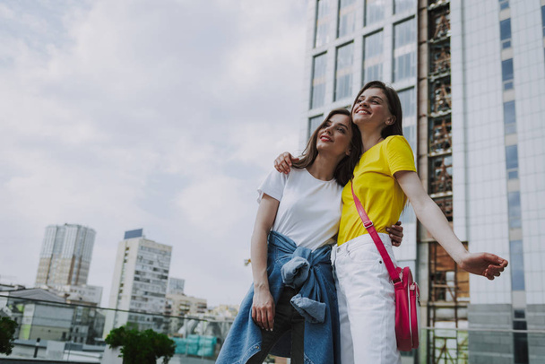 Two happy hipster girls embracing on city view - Фото, зображення