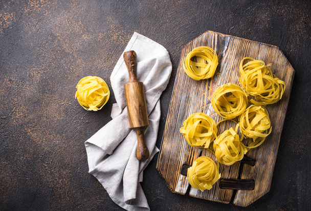 Raw pasta tagliatelle or fettuccine - Foto, afbeelding