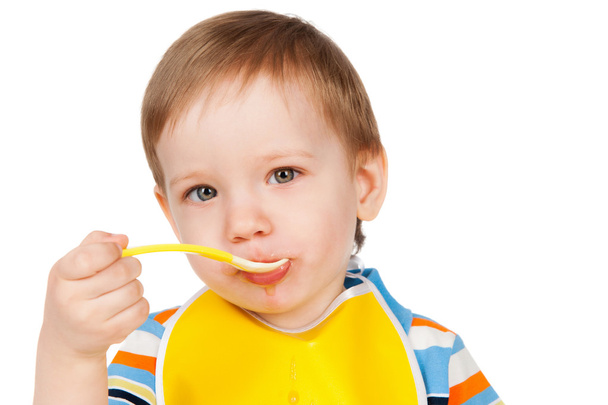 Boy eats with a spoon puree - Foto, afbeelding
