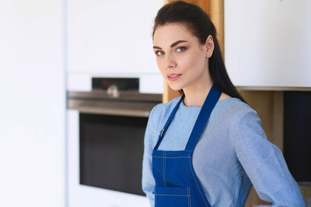 Portrait of young woman standing with arms crossed against kitchen background - Fotoğraf, Görsel