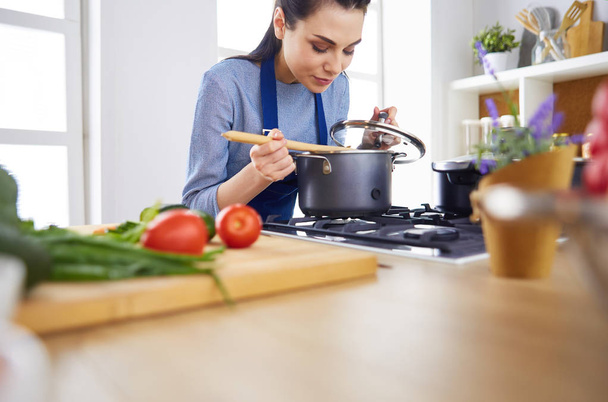 Cooking woman in kitchen with wooden spoon - Valokuva, kuva