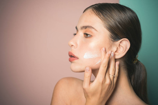 Keep skin hydrated regularly moisturizing cream. Taking good care of her skin. Beautiful woman spreading cream on her face. Skin cream concept. Facial care for female. Fresh healthy skin concept - Photo, image