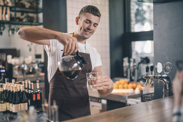 Barista sorridente guardando fiducioso mentre versava caffè fresco
 - Foto, immagini