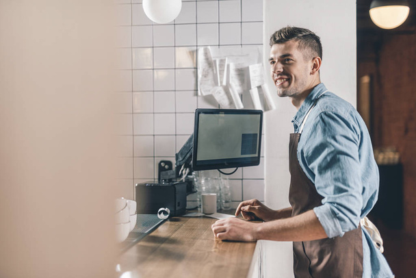 Cheerful barista smiling while standing in front of the bar counter - Foto, Bild