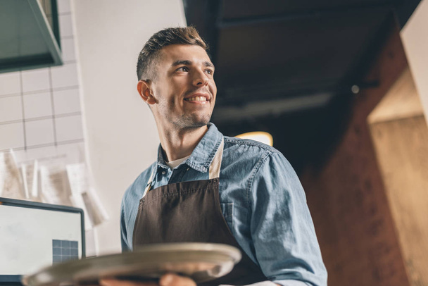 Cameriere sorridente con vassoio che guarda in lontananza
 - Foto, immagini