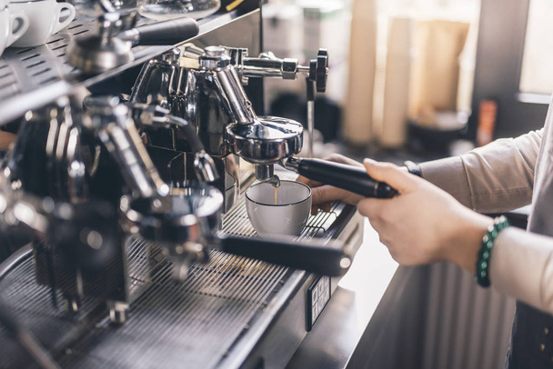 Coffee pouring from the espresso machine to white cup - Fotoğraf, Görsel