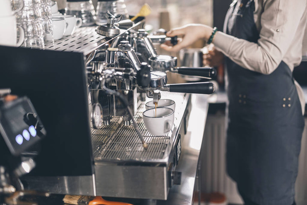 Coffee pouring into the cups while barista standing near - Photo, Image