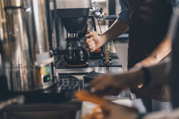 Hand of barista taking coffee jug by the handle - Photo, Image