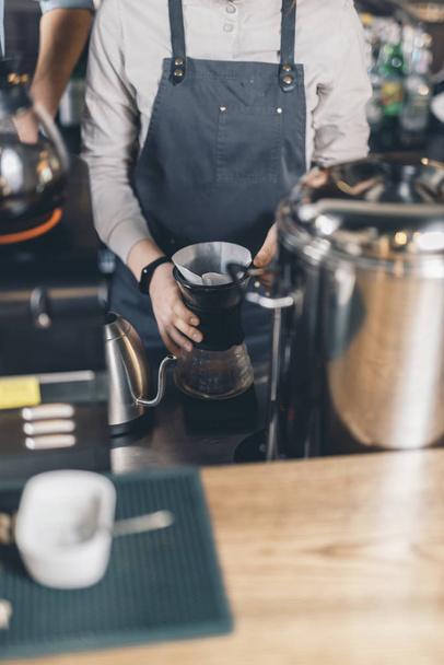 Hands of barista making pour over coffee at the bar counter - 写真・画像