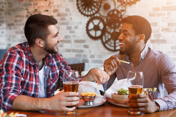Отдых в баре. Мужчины пьют пиво и едят картошку фри
 - Фото, изображение