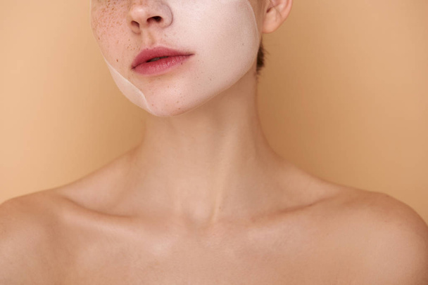 Young woman with white mask on her face standing against beige background - Foto, Imagem