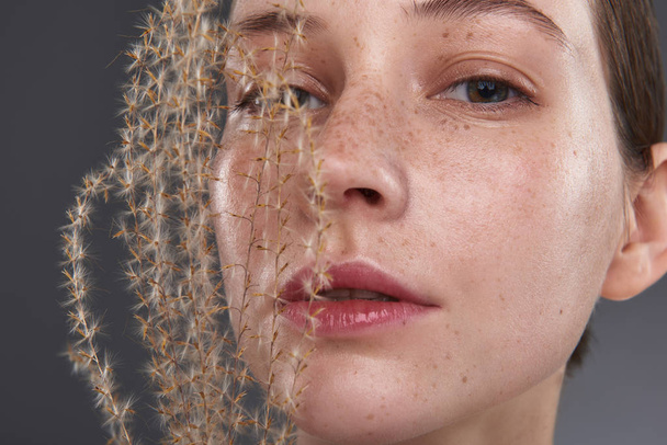 Beautiful young woman with freckles holding fluffy sprig - Photo, Image