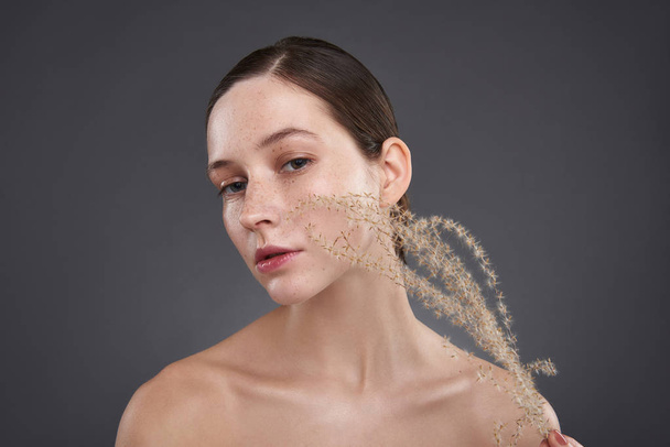 Beautiful young woman with freckles holding fluffy sprig - Φωτογραφία, εικόνα