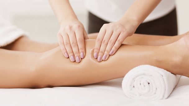Sport massage. Therapeut masserende vrouw kalveren, close-up - Foto, afbeelding