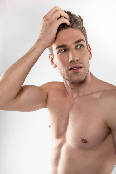 Handsome young man with perfect body touching his hair - Foto, imagen