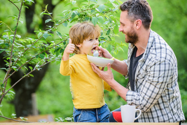 Family enjoy homemade meal. Father son eat food and have fun. Little boy and dad eating. Nutrition for kids and adults. Healthy nutrition concept. Feeding baby. Menu for children. Nutrition habits - 写真・画像