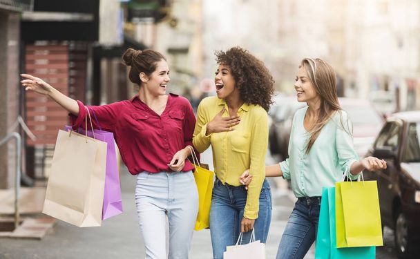 Jovens mulheres caminhando com sacos de compras na rua
 - Foto, Imagem