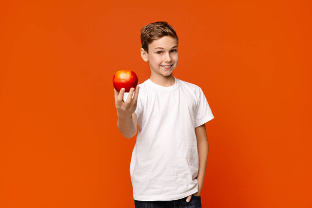 Menino positivo oferecendo maçã vermelha fresca na câmera
 - Foto, Imagem