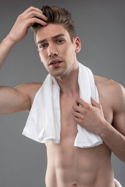 Attractive young man with towel adjusting his hair - Zdjęcie, obraz
