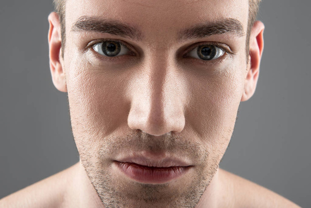 Handsome young man with stubble standing against blue-gray background - Fotoğraf, Görsel