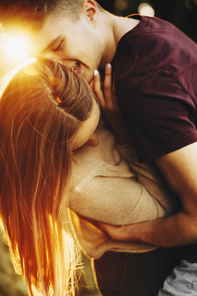 Απίστευτο κοντινό πορτραίτο ενός όμορφου νεαρού καυκάσιο ζευγάρι που αγκαλιάζει και έχει τη διασκέδαση κατά του ηλιοβασιλέματος. - Φωτογραφία, εικόνα