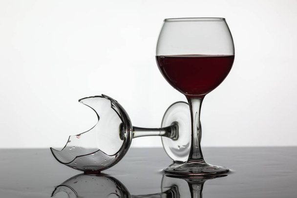 Lleno de una copa de vino y copa de vino roto con vino tinto
 - Foto, imagen