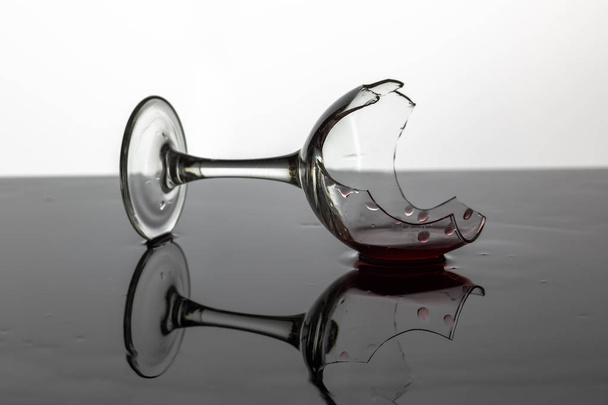 Copa de vino roto con vino tinto que se encuentra en la superficie húmeda
 - Foto, imagen