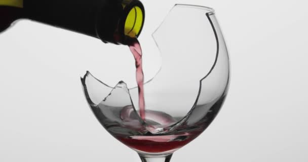 Viiniä. Punaviini kaadetaan rikkoutuneeseen viinilasiin valkoisella pohjalla
 - Materiaali, video