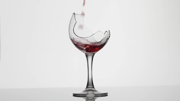 Wine. Red wine pouring in broken wine glass on the white background - Footage, Video