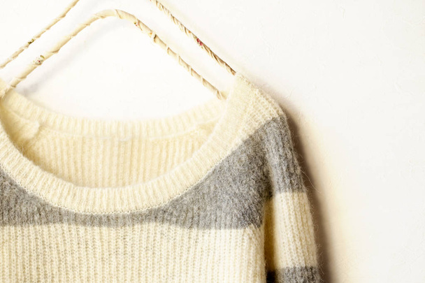 White and gray striped sweater hanging on clothes hanger on white background. - Fotografie, Obrázek