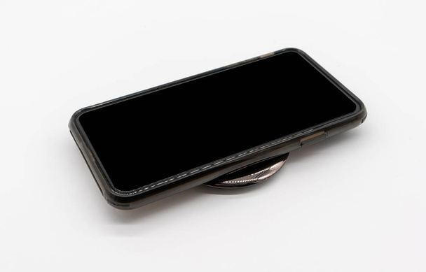 Μαύρο κινητό τηλέφωνο φορτίζει στο μαύρο στρογγυλό σχήμα ασύρματο - Φωτογραφία, εικόνα