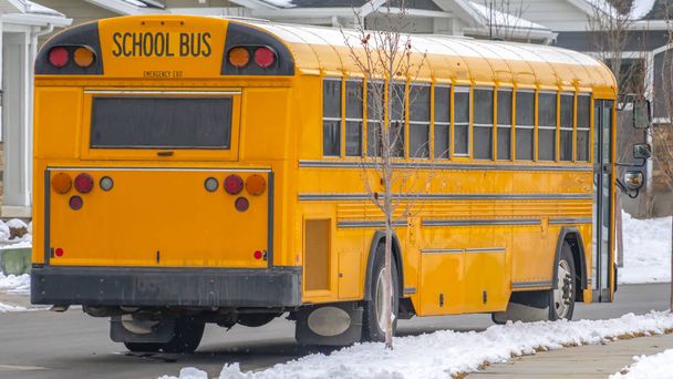 Панорама Вид на жовтий шкільний автобус, що біжить по дорозі зі свіжим снігом взимку
 - Фото, зображення