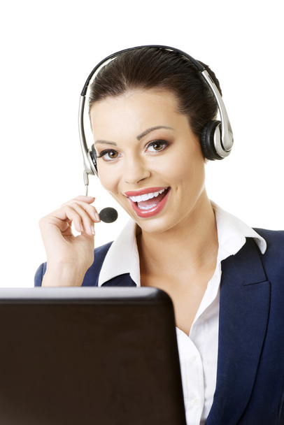 Beautiful young call-center assistant at the desk - Фото, изображение