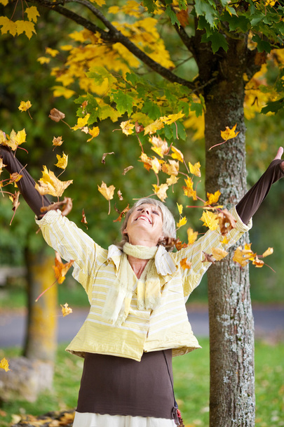 Autumn Leaves Falling On Senior Woman - Фото, зображення