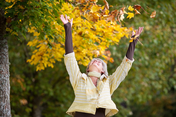 Autumn Leaves Falling On Happy Senior Woman - Φωτογραφία, εικόνα