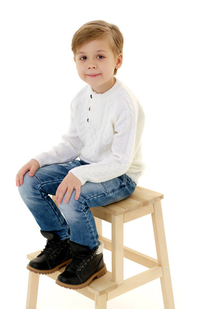 A little boy is sitting on a chair. - Foto, imagen
