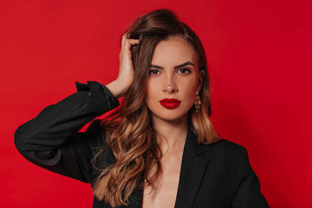 schöne Frau Gesicht Nahaufnahme Porträt junge lockige Haare Studio auf rotem Hintergrund mit roten Lippen und gebräunter Haut  - Foto, Bild